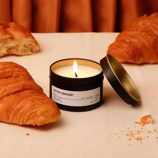Candle labeled 'Buttery Croissant' with croissants on a white surface